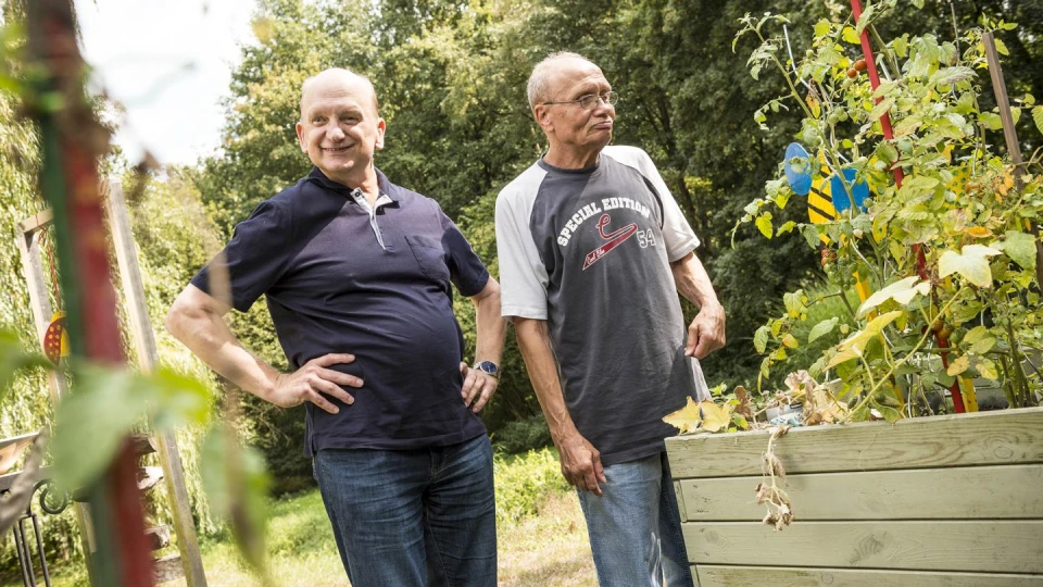 Zwei Senioren die im garten vor einem Hochbeet stehen.