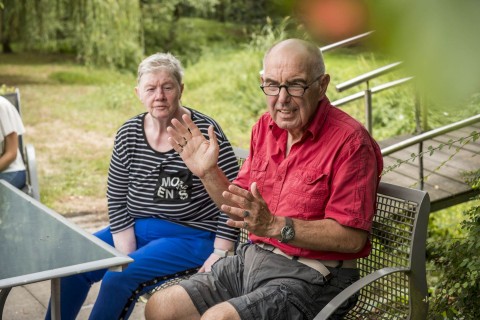 Zwei Senioren sitzen zusammen auf einer Bank.