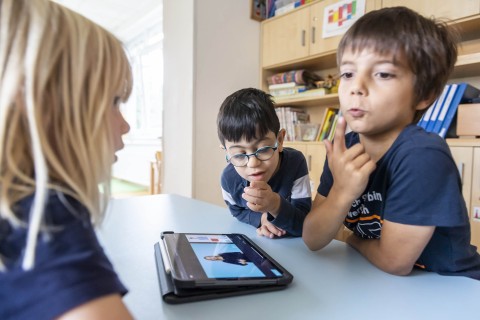 3 Kinder, die sich SIFN Symbole auf dem Tablet angucken