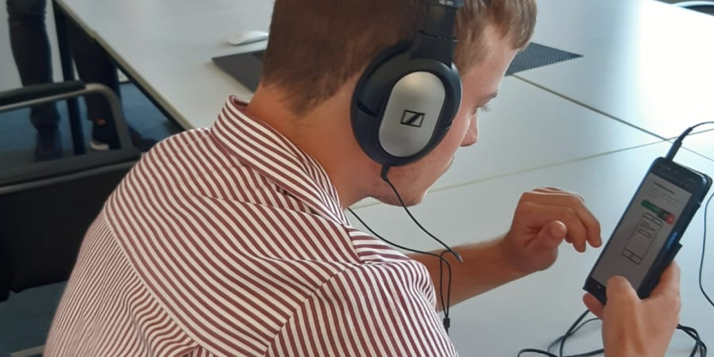 Eine Junge, der an einem Handy, die mit Kopfhörern verbunden sind, sitzt