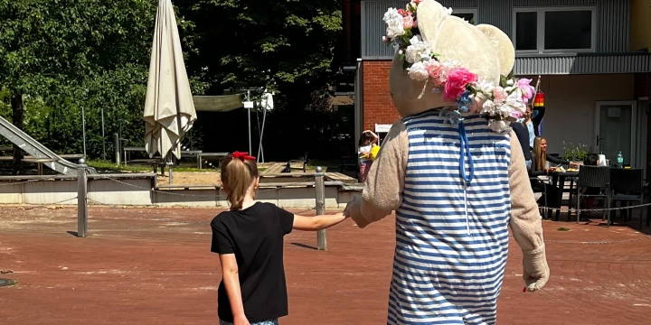 Ein M&auml;dchen mit einem als Pl&uuml;schtier verkleideten Menschen.