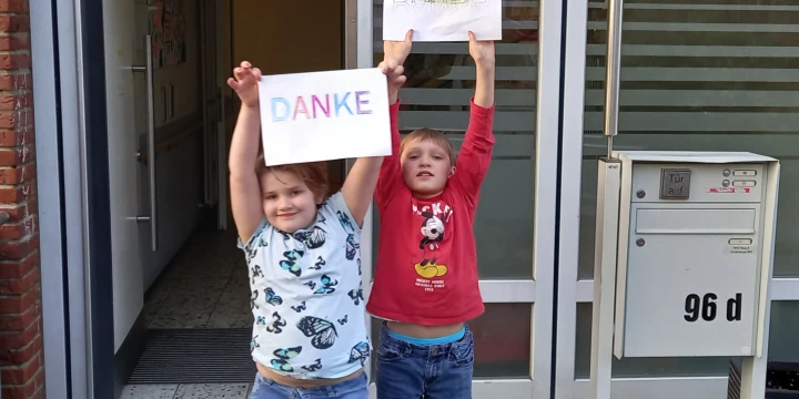 Zwei Kinder halten Schilder mit der Aufschrift Danke hoch.