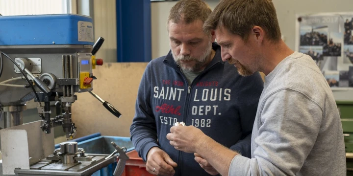 Thomas Uhlen und ein Mitarbeiter der Werkstatt Schledehausen an einer Maschine.