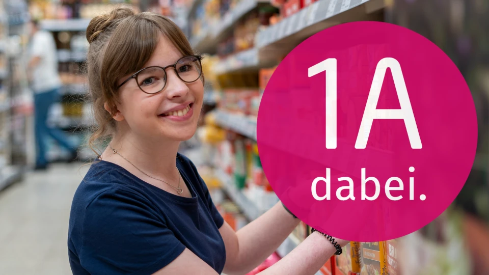 Marie Lindenthal in einem Gang im nahkauf. Daneben das Logo von 1A - ein Arbeitsmarkt f&uuml;r alle.