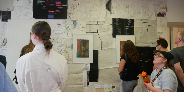Menschen die sich Ausstellungsbilder in der StudioGalerie anschauen.