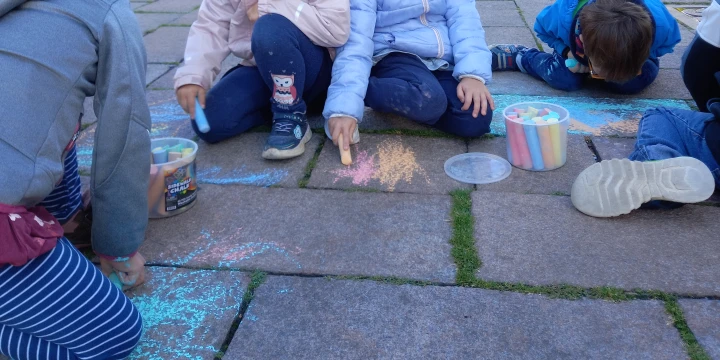 Mehrere Kinder malen mit Stra&szlig;enkreide