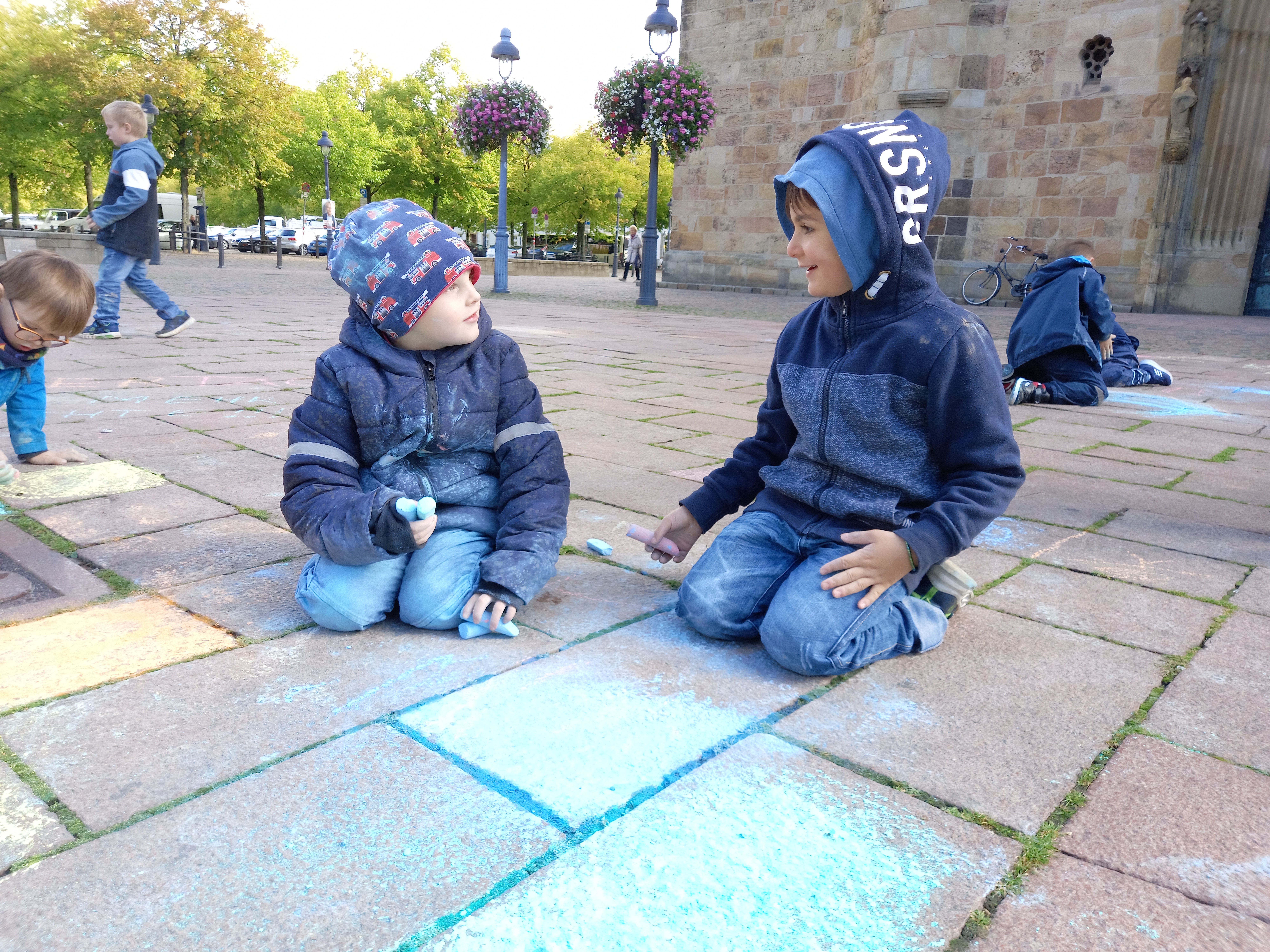 Mehrere Kinder malen mit Straßenkreide