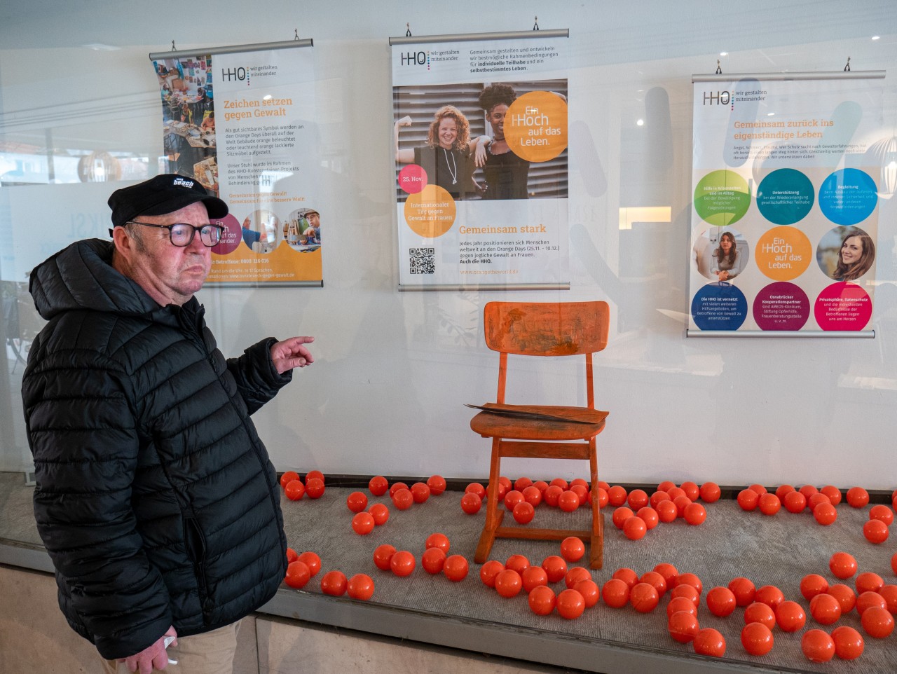 Mann, der auf einen orangen Stuhl in einem Schaufenster zeigt.