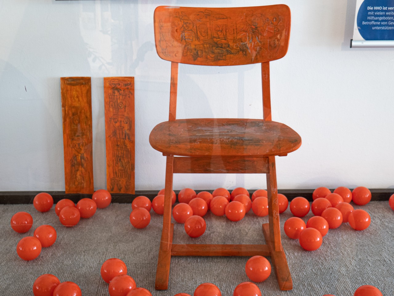 Orangener Stuhl steht in einem Schaufenster mit orangenen Spielbällen