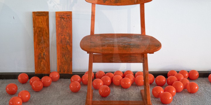 Orangener Stuhl steht in einem Schaufenster mit orangenen Spielbällen