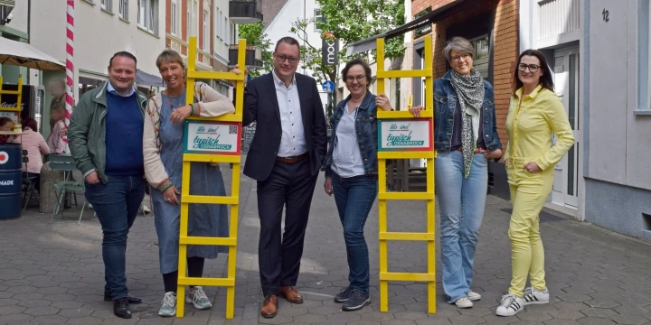 Mehrere Menschen mit zwei Osnabr&uuml;cker Leitern, als Hinweis auf regionale Produkte.