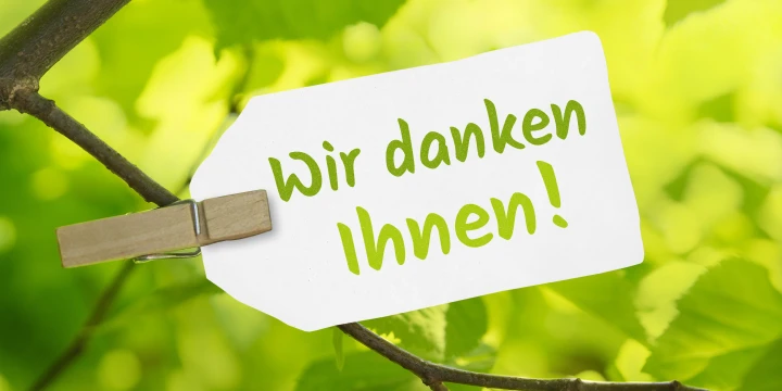 Karte, die an einem Ast h&auml;ngt mit der Aufschrift "Wir danken Ihnen!"