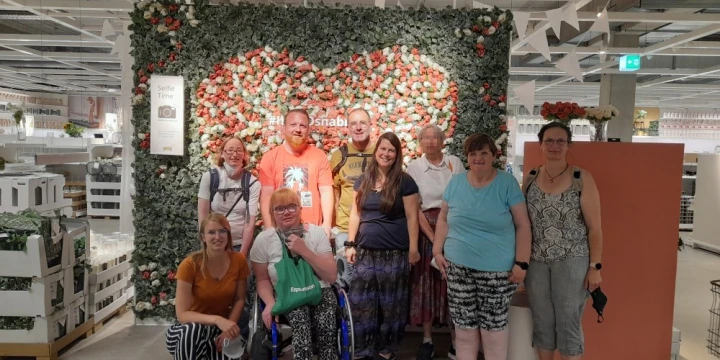 9 Personen stehen vor einer Blumenwand im IKEA