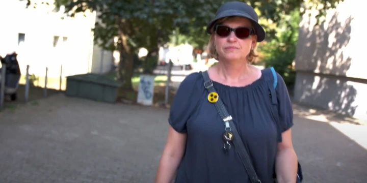 Frau mit Sonnenbrille und Blindenabzeichen ist drau&szlig;en unterwegs