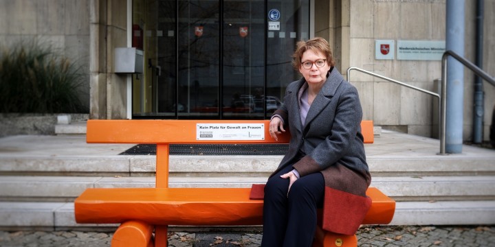 Eien Frau, die auf einer orangenen Bank mit der Aufschrift "kein Platz für Gewalt an Frauen" sitzt