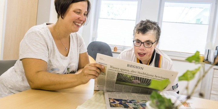 Eine Frau und eine Betreuerin lesen Zeitung
