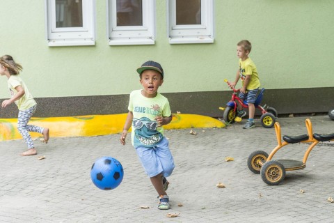 drei Kinder spielen auf dem Hof des Kindergartens